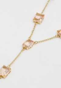 Zlatna ogrlica koja sadrži četiri pravokutna i jedan ovalni ružičasti dragi kamen, povezani delikatnim lančićem. Glatka površina s sjajnim finišom.