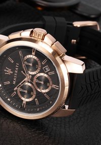 Orologio cronografo Maserati con quadrante nero, dettagli in oro rosa, cinturino in gomma e cassa testurizzata con più quadranti secondari.