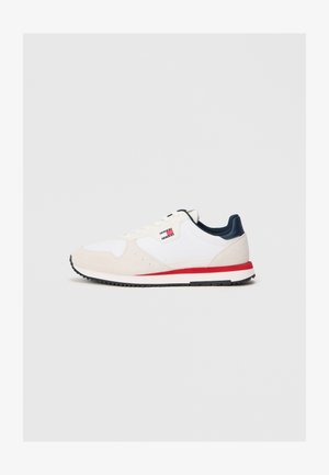 Białe buty sportowe z zamszową i tekstylną cholewką, granatowymi akcentami, czerwoną linią na podeszwie oraz perforowanymi detalami.