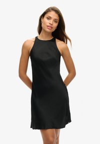 Czarna sukienka na halter z gładkiego materiału, z dopasowaną górą i rozkloszowanym dołem, o długości do kolan i minimalistycznym designie.