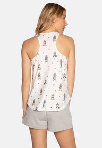 White tank top with dog illustrations in red, blue, and star patterns; racerback design; paired with gray shorts. Soft fabric, casual fit.