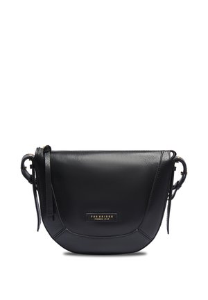Sac bandoulière en cuir noir avec rabat incurvé, sangle ajustable et petite plaque dorée avec le logo "The Bridge Firenze 1969" sur le devant.