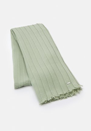 Hellgrüner, gerippter Strickschal mit Fransen an den Enden, zusammengefaltet auf weißem Hintergrund, mit einer kleinen rechteckigen silbernen Marke.