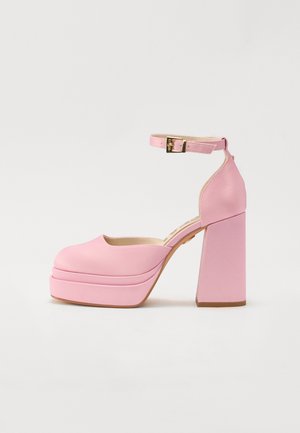 Rozā augstpapēžu platformas kurpes ar noapaļotu purngalu, potītes siksniņu un bloku papēdi. Gluda materiāla ar smalku faktūru un zelta sprādzi.