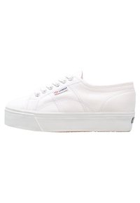 Baskets à plateforme en toile blanche avec bout rond, lacets à l'avant, semelle texturée et détails de couture subtils ; étiquette de marque sur le côté.