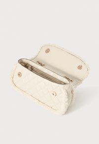 Gequilte crèmekleurige handtas met een faux fur rand, voorzien van gouden hardware en een ritssluiting aan de binnenkant. Geopend om de ruime binnenkant te tonen.