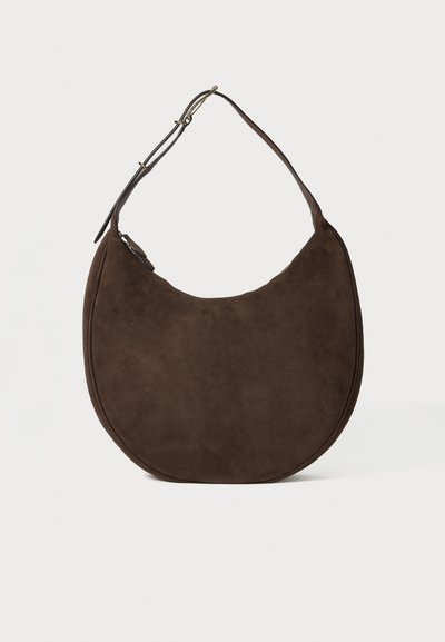Brown suede shoulder bag with a crescent shape, featuring a single shoulder strap and a smooth texture. Zippered closure detail.