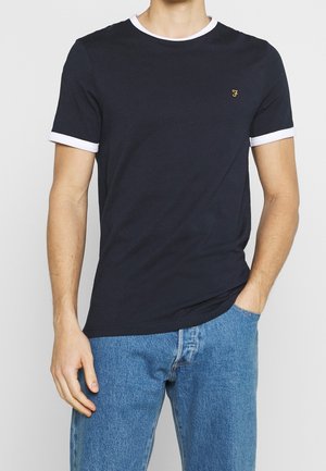 Camiseta azul marino con cuello y puños blancos, escote redondo, mangas cortas, de algodón, con un pequeño logo dorado en el pecho.