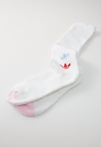 Calze bianche a coste con accenti rosa sulle punte e un design floreale blu e rosso vicino alla parte superiore.