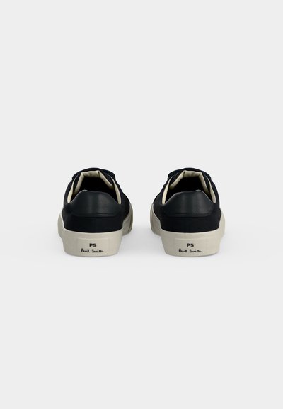 Baskets basses noires avec semelles blanc cassé vues de dos, montrant le logo PS Paul Smith sur la languette du talon de chaque chaussure.