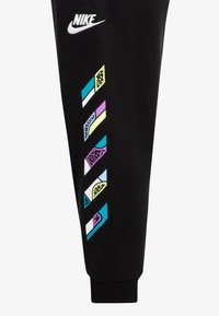 Los pantalones de chándal negros de Nike presentan un diseño lateral de patrones geométricos coloridos en azul, verde neón, púrpura y blanco. Los puños acanalados en los tobillos completan el look.