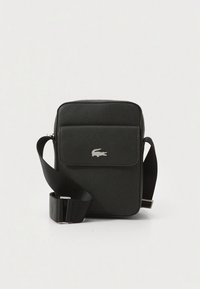 Black textured crossbody bag with flap pocket featuring silver crocodile logo and adjustable wide strap on a plain light background.