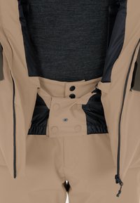 Giacca beige con zip frontale, bottoni a pressione e rivestimento in rete nera. Texture liscia con caratteristiche regolabili e tasche.