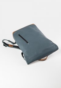 Grau Leder Rucksack mit glatter Textur, hellbraunen Akzenten und einer Front-Reißverschlusstasche; verstellbare Träger für mehr Komfort.
