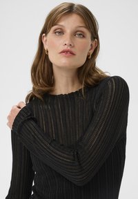 Pull noir en tricot côtelé avec un design texturé, col en U et manches ajustées présentant un motif de rayures subtil.