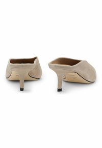 Beige suede high-heeled mules with a pointed toe, open back, and thin black heel. Smooth texture and minimalistic design.