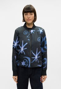 Veste bomber noire avec des motifs bleus d'étoiles et de lunes, fermeture éclair et poignets et col côtelés pour un design ajusté.