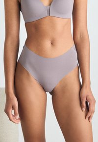 Sous-vêtements en nylon violet clair avec un design échancré, texture lisse et coutures minimales, mettant en avant des lignes épurées et une forme simple.