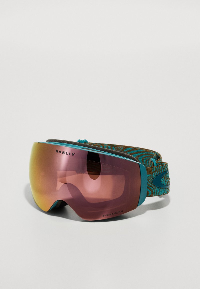 Maschera da sci con una grande lente curva di colore rosa e dettagli turchesi. Presenta un cinturino marrone testurizzato con un motivo vorticoso.