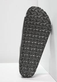 Grå gummisula med en strukturerad design med vågmönster. Stabil och flexibel, med en slät kant och rund tåform.