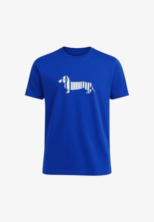 Maglietta azzurra a maniche corte con grafica di un bassotto bianco con strisce verticali lungo il corpo, posizionata sul petto.