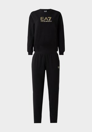 Zwart sweatoutfit bestaande uit een sweatshirt met ronde hals en gouden logo, en bijpassende, taps toelopende broek met een elastische tailleband, gemaakt van zachte stof.