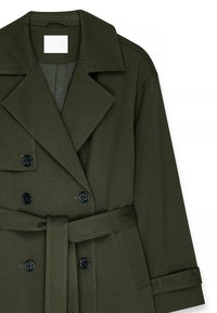 Double-breasted trench coat in dark green fabric with a belt. Features large lapels, black buttons, and a textured surface.