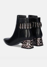 Botas de tobillo de cuero negro con punta afilada, con acentos metálicos y tacones bloqueados con patrón en tonos plateados y negros.