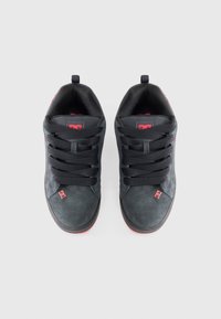 Sorte ruskindssneakers med sorte snørebånd, røde accenter og en tekstureret tåhætte. Har et lille logo-tag på siden og en polstret krave.