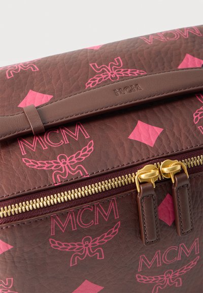 Sac en cuir marron avec logos et motifs roses MCM, doté de tirettes de fermeture éclair dorées et d'une poignée en cuir cousue embossée du nom "MCM."