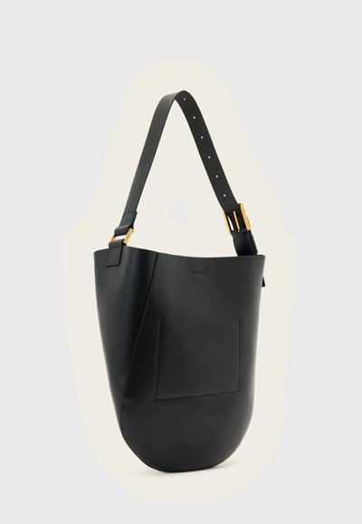 Sac seau en cuir noir avec bandoulière réglable et boucle dorée sur un fond clair uni.