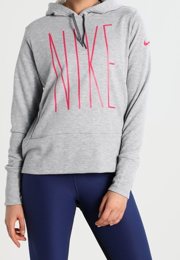Un sweat à capuche gris avec le lettrage "NIKE" en rose, doté d'une capuche avec cordon de serrage et d'une poche kangourou à l'avant. Porte sur un legging noir. Texture du tissu douce.