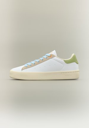 Biały niskoprofilowy sneaker z jasnoniebieskimi sznurowadłami, beżowymi akcentami, zielonym paskiem na pięcie i kremową gumową podeszwą na neutralnym tle.