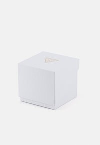 Caja cuadrada blanca con una superficie texturada, con un logo triangular dorado en la parte superior, diseñada para embalaje.