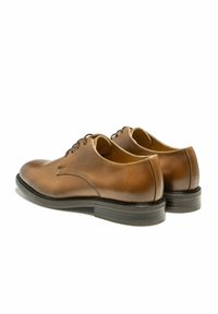 Chaussures en cuir marron avec une finition lisse, lacets plats et bout arrondi. Présentent un talon empilé et un design minimaliste.