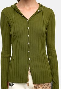 Oliwkowozielony kardigan z prążkowanej tkaniny, z kapturem, z zapięciem na guziki i długimi rękawami. Charakteryzuje się subtelną teksturą oraz dopasowanym krojem.