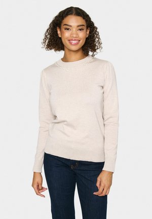 Light beige sweater with a round neckline and decorative beads along the collar. Long sleeves, fitted silhouette, soft texture, paired with dark jeans.