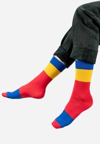 Kolorowe skarpety w czerwone, żółte i niebieskie paski. Wykonane z gładkiego, elastycznego materiału, przy czym każda skarpeta ma wyraźnie wyróżniające się kolorowe segmenty.