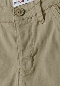 Beige Baumwollshorts mit einer glatten Textur, einer Vordertasche und einem Knopfverschluss. Enthält ein Markenetikett mit Stichdetails.