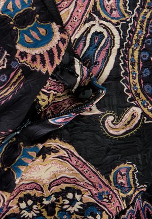 Sort stof med et farverigt paisley-mønster i pink, blå og creme, med synlige folder, en knap og lynlåsdetaljer.