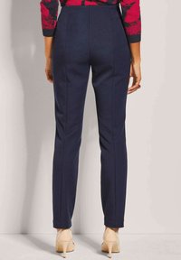 Marineblauwe op maat gemaakte broeken met een slim fit, voorzien van naaddetails, een hoge taille en een zachte textuur. Gepaarde met lichtkleurige hakken.