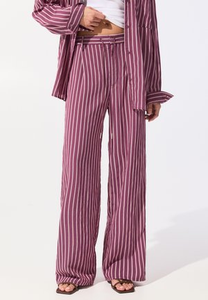 Chemise rayée violette et pantalon large assorti en tissu léger, présentant des rayures verticales et une taille ceinturée avec des détails subtils.