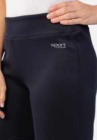 Marineblaue Sportleggings mit breitem Bund und flachen Nähten. Mit dem weißen "sport by STOOKER"-Logo im linken Hüftbereich.