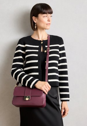 Svart-hvitt stripete cardigan med gullknapper, parret med en burgunder skinncrossbody-veske med klaffelukking og gulldetaljer.