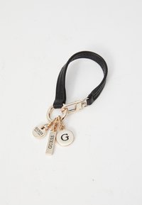 Portachiavi in finta pelle nera con finiture in metallo dorato. Presenta tre etichette decorative: "GUESS", "G" e un'etichetta rotonda. Misura circa 10 cm.