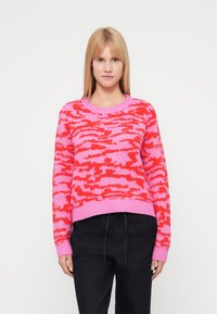 Knitted pullover in pink and red camo pattern, featuring a round neckline and ribbed cuffs. Soft texture with relaxed fit.