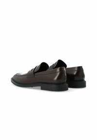 Mocassins en cuir marron avec une finition brillante, bout arrondi et semelle en caoutchouc noire basse. Une sangle en selle sur le dessus ajoute du détail.