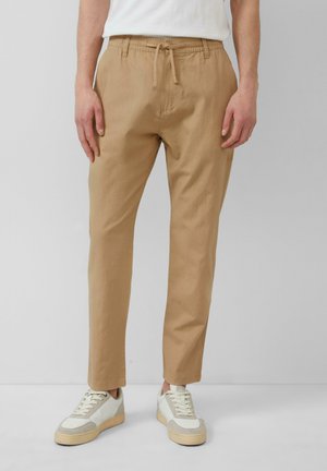 Beige, broek met elastische taille en trekkoord, getailleerde pasvorm, lichte stof, gecombineerd met witte en beige sneakers.