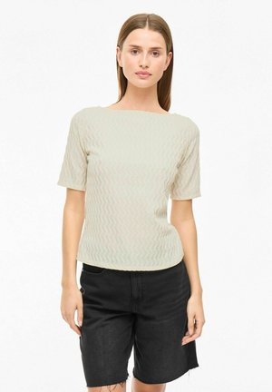 Lätt texturerad topp med en vågformad mönster, korta ärmar och båtformad halsringning, matchad med högmidjade svarta jeansshorts.