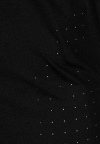 Schwarzer Stoff mit kleinen weißen Punkten, die überall verteilt sind, zeigt eine glatte Textur und leichte Drapierung. Keine sichtbaren Muster oder Hardware.